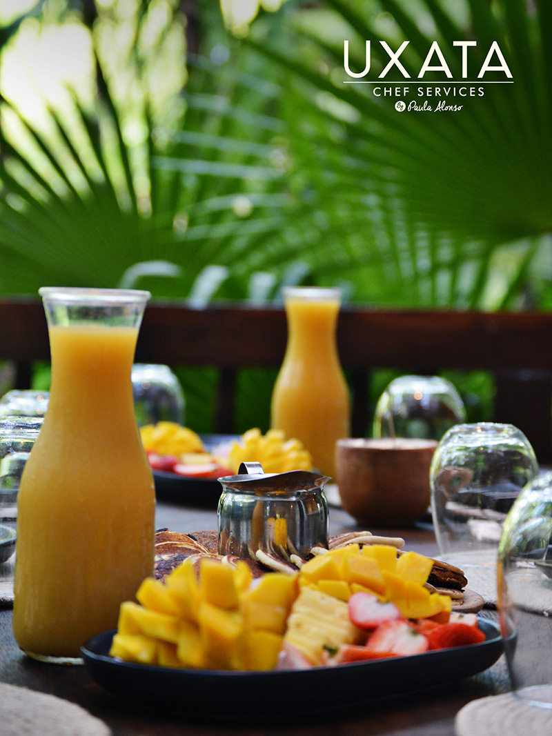 Un desayuno con jugo de naranjas y mango, frutas tropicales, servido en la mesa por UXATA Servicios de Chef Privado, Riviera Maya, México.